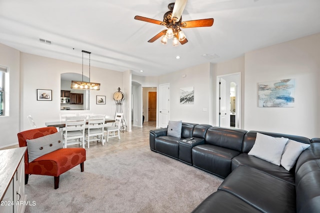 living room featuring arched walkways, recessed lighting, light colored carpet, visible vents, and a ceiling fan