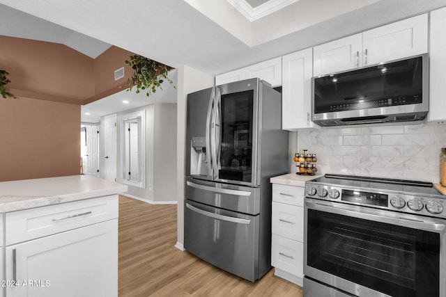 kitchen with lofted ceiling, white cabinets, tasteful backsplash, light wood-type flooring, and stainless steel appliances