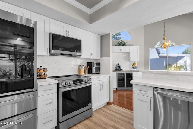 kitchen featuring appliances with stainless steel finishes, wine cooler, a healthy amount of sunlight, and white cabinetry