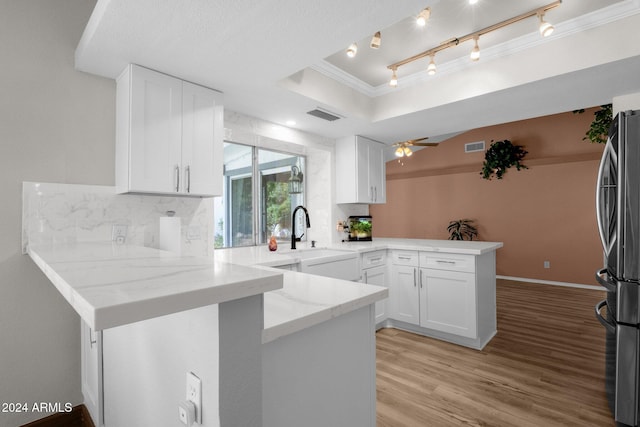 kitchen featuring kitchen peninsula, stainless steel fridge, sink, white cabinetry, and light hardwood / wood-style floors