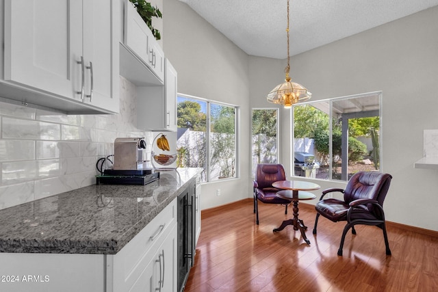 kitchen with white cabinets, a textured ceiling, wood-type flooring, pendant lighting, and a notable chandelier