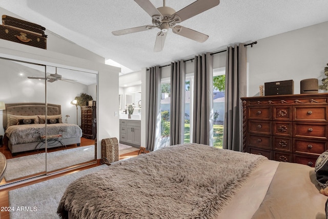 bedroom featuring lofted ceiling, hardwood / wood-style flooring, a closet, a textured ceiling, and ceiling fan