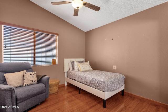 bedroom with ceiling fan, a textured ceiling, vaulted ceiling, and hardwood / wood-style floors