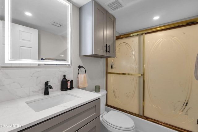 full bathroom with vanity, toilet, tasteful backsplash, and combined bath / shower with glass door