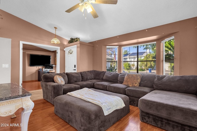 living room featuring lofted ceiling, a textured ceiling, light hardwood / wood-style floors, and ceiling fan