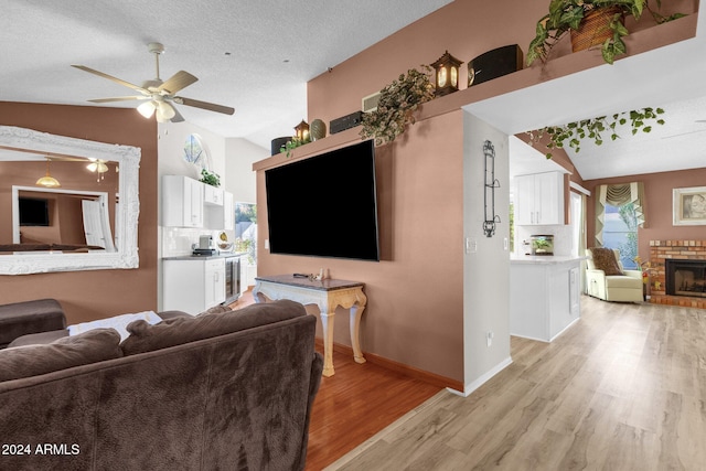 living room featuring ceiling fan, a wealth of natural light, light wood-type flooring, and vaulted ceiling