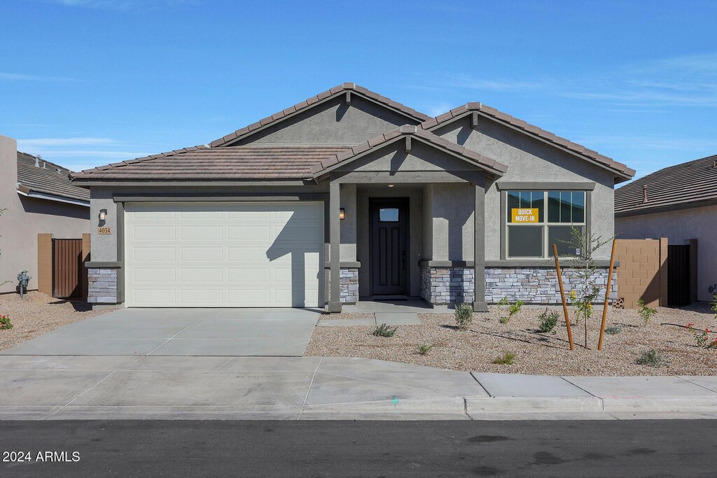 view of front facade with a tile roof, stucco siding, concrete driveway, a garage, and stone siding