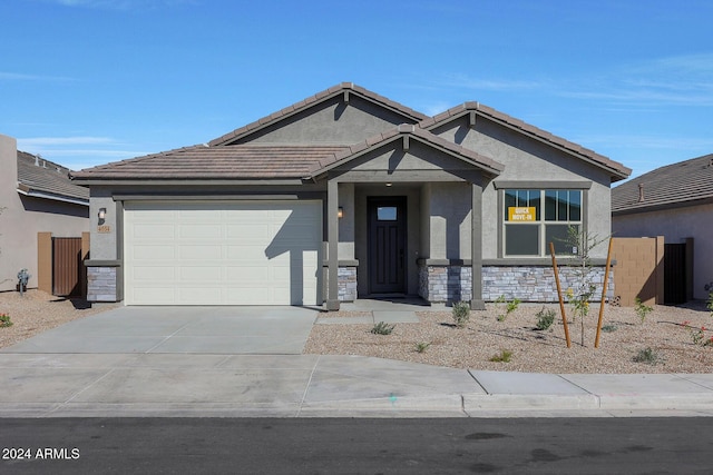 view of front facade with a tile roof, stucco siding, concrete driveway, a garage, and stone siding