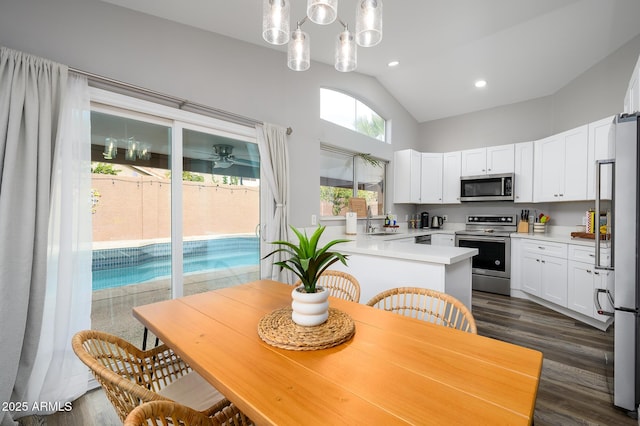 kitchen with white cabinetry, sink, kitchen peninsula, decorative light fixtures, and appliances with stainless steel finishes