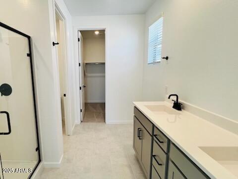 25137 W Wayland Dr, Buckeye, AZ 85326 - bathroom featuring a stall shower, double vanity, baseboards, and a spacious closet