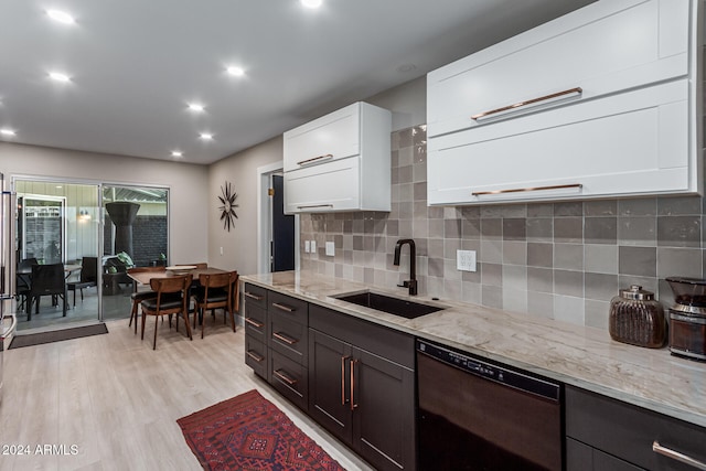 kitchen featuring light stone counters, white cabinetry, dishwasher, light hardwood / wood-style floors, and sink