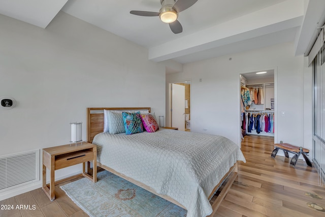 bedroom featuring a spacious closet, a closet, light wood-type flooring, and ceiling fan