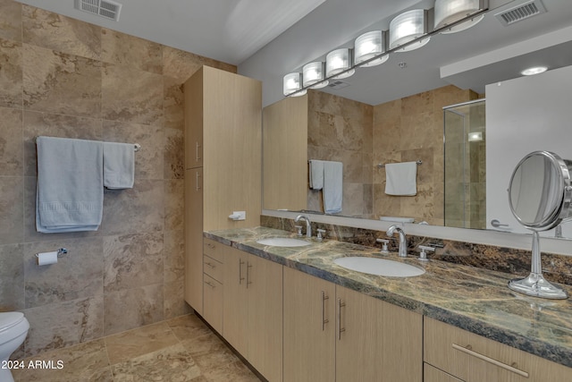 bathroom featuring tile walls, vanity, a shower with shower door, and toilet