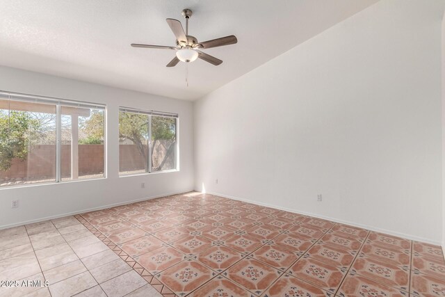 empty room featuring light tile patterned flooring, baseboards, vaulted ceiling, and ceiling fan