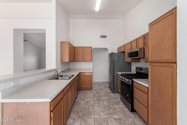 kitchen featuring light countertops, marble finish floor, appliances with stainless steel finishes, a sink, and a high ceiling
