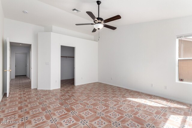 unfurnished bedroom featuring light tile patterned flooring, a closet, a walk in closet, baseboards, and visible vents
