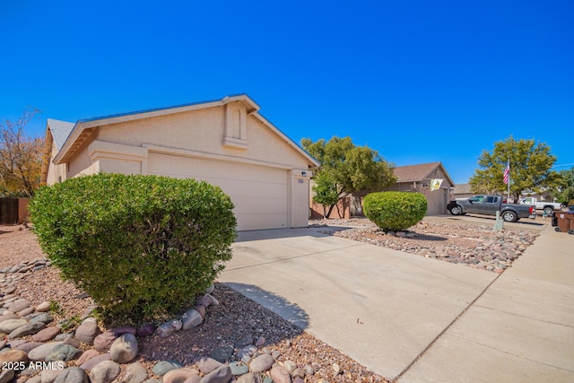 view of side of home featuring a garage, concrete driveway, and stucco siding