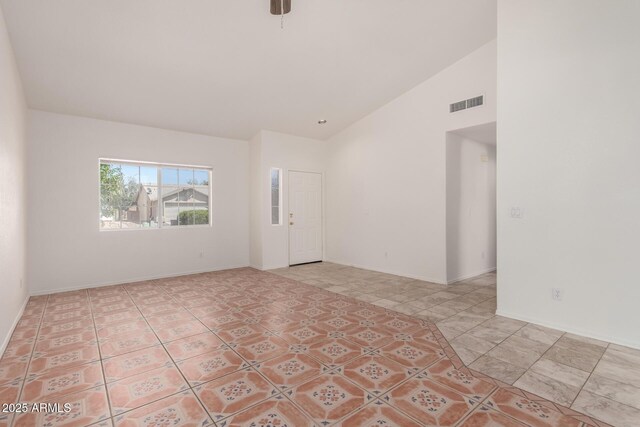 spare room featuring baseboards, high vaulted ceiling, and visible vents