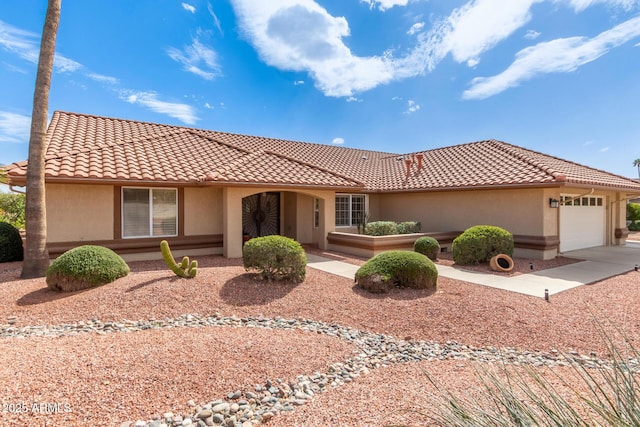 view of front of home featuring an attached garage, driveway, a tile roof, and stucco siding