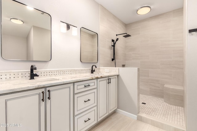 full bath with a sink, a tile shower, and double vanity