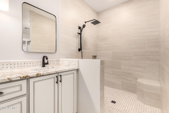 bathroom with a tile shower and vanity