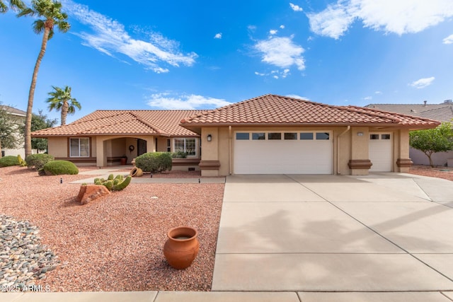 view of front of home featuring driveway, an attached garage, a tile roof, and stucco siding