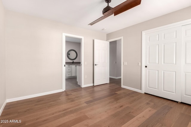 unfurnished bedroom with a sink, wood finished floors, a ceiling fan, and baseboards