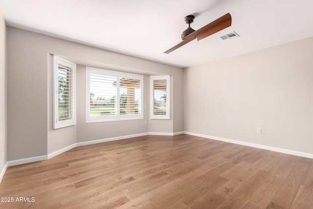 spare room with light wood-style floors, baseboards, visible vents, and a ceiling fan