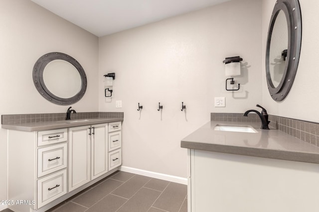 bathroom with tile patterned flooring, baseboards, two vanities, and a sink