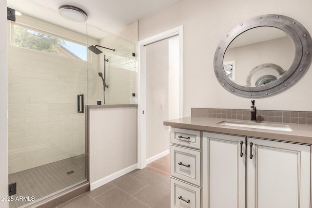 bathroom with tile patterned flooring, baseboards, a shower stall, and vanity