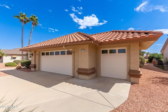 mediterranean / spanish-style home with driveway, an attached garage, a tile roof, and stucco siding