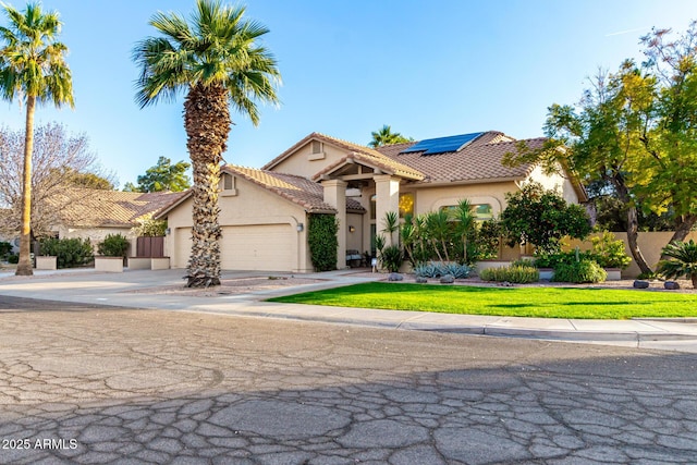 mediterranean / spanish-style home with a garage, a front lawn, and solar panels