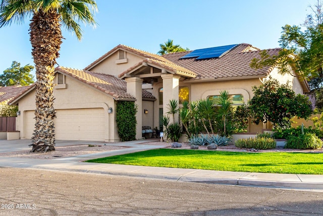 mediterranean / spanish house featuring a garage, a front lawn, and solar panels