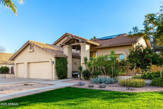 mediterranean / spanish home with a garage, a front lawn, and solar panels