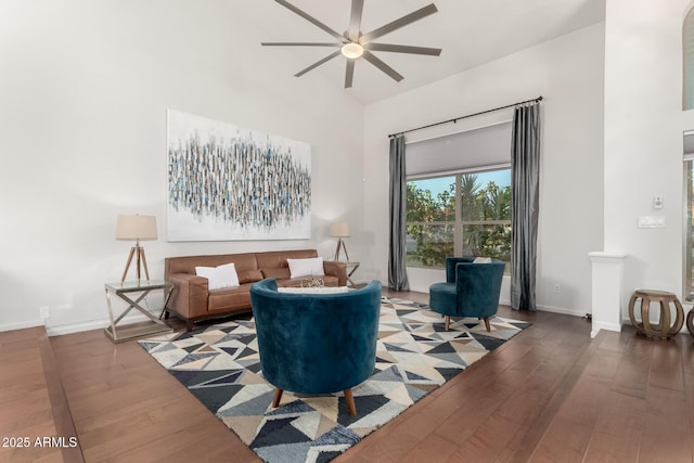 living room with ceiling fan, hardwood / wood-style floors, and a high ceiling