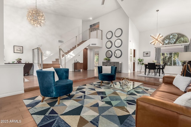 living room with a towering ceiling, an inviting chandelier, and light hardwood / wood-style flooring