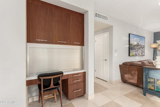 home office featuring light tile patterned floors and built in desk