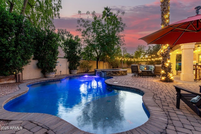 pool at dusk featuring an in ground hot tub, pool water feature, and a patio