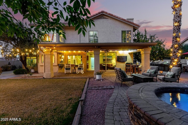 back house at dusk with a fenced in pool, outdoor lounge area, and a patio area