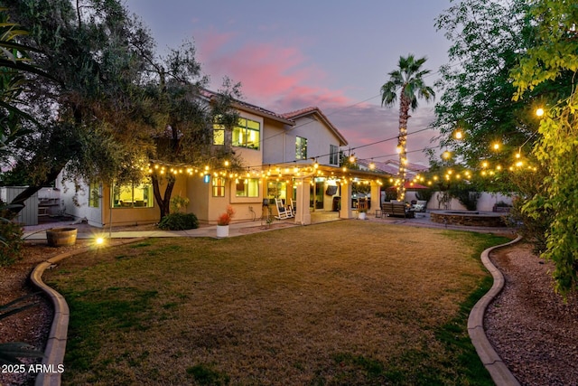 back house at dusk with outdoor lounge area, a yard, and a patio area