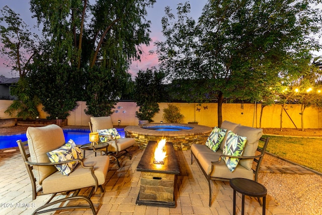 patio terrace at dusk featuring a fenced in pool and an outdoor living space with a fire pit