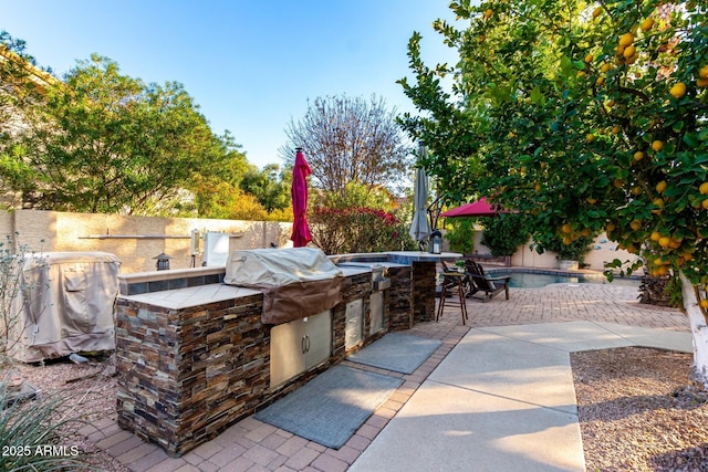 view of patio / terrace featuring a fenced in pool, grilling area, an outdoor bar, and an outdoor kitchen