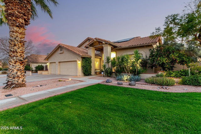 view of front of home with a garage, a yard, and solar panels