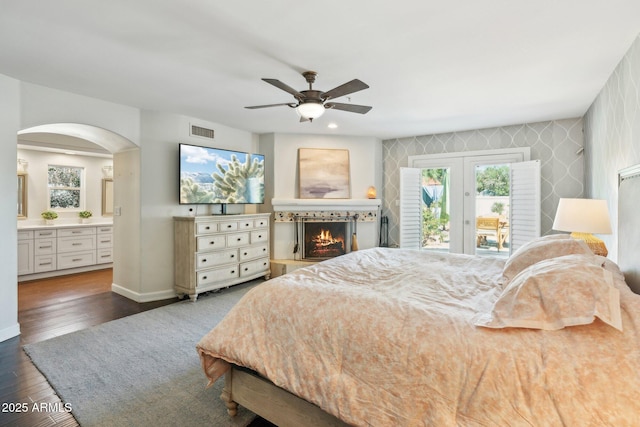 7214 E Royal Palm Rd, Scottsdale, AZ 85258 - bedroom featuring access to outside, arched walkways, a warm lit fireplace, wood finished floors, and baseboards
