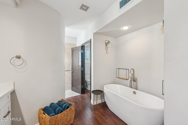7214 E Royal Palm Rd, Scottsdale, AZ 85258 - bathroom with a freestanding bath, vanity, wood finished floors, toilet, and a shower with shower door