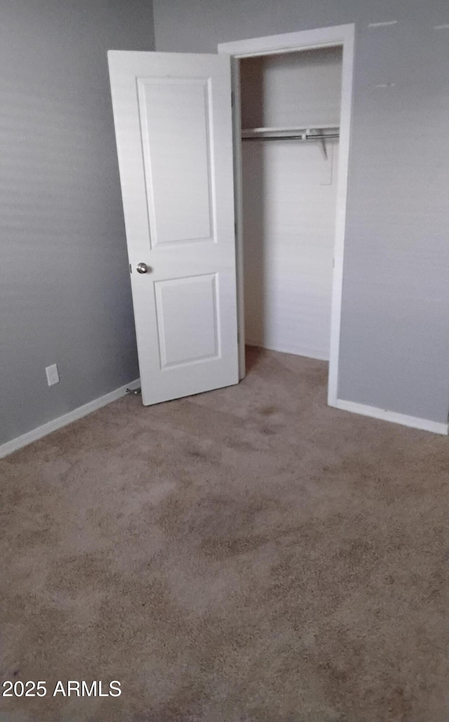 unfurnished bedroom with carpet, a closet, and baseboards