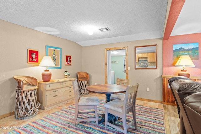dining room featuring baseboards, visible vents, and a textured ceiling