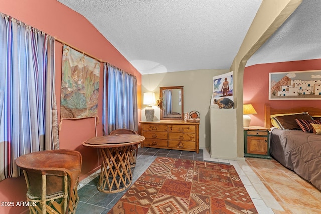 interior space with tile patterned floors, a textured ceiling, and lofted ceiling