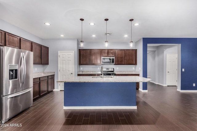 kitchen featuring a center island with sink, dark hardwood / wood-style floors, decorative light fixtures, and appliances with stainless steel finishes