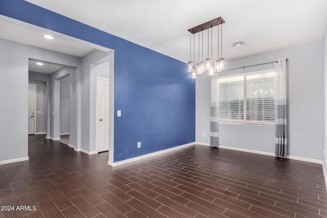 empty room featuring dark hardwood / wood-style flooring and a chandelier